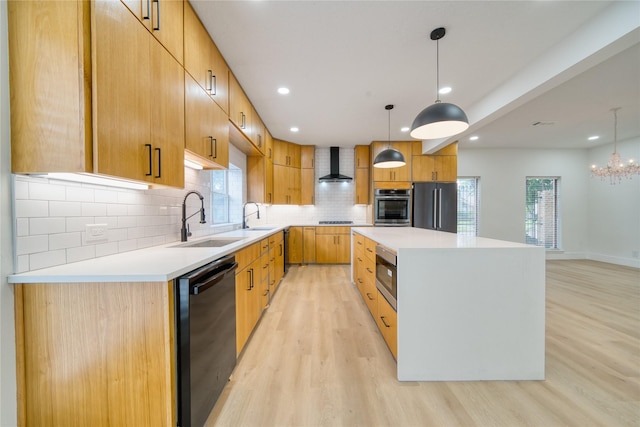 kitchen featuring a kitchen island, wall chimney exhaust hood, a sink, light wood-style flooring, and stainless steel appliances