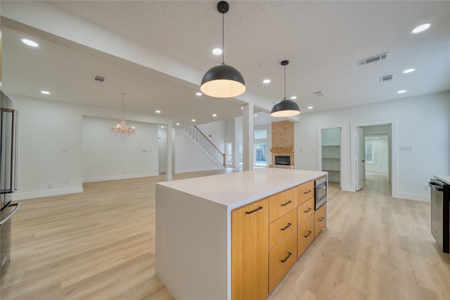 7906 Duffield Ln, Houston, TX 77071 - kitchen with a fireplace, open floor plan, light wood-style floors, modern cabinets, and pendant lighting