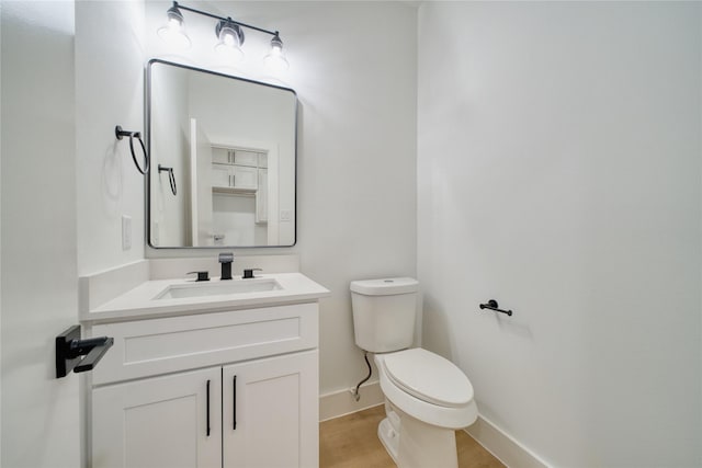 bathroom with baseboards, vanity, toilet, and wood finished floors
