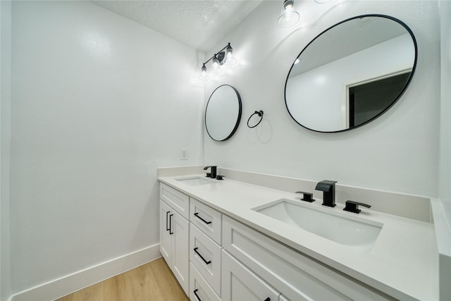 7906 Duffield Ln, Houston, TX 77071 - bathroom featuring wood finished floors, a textured ceiling, baseboards, and double vanity
