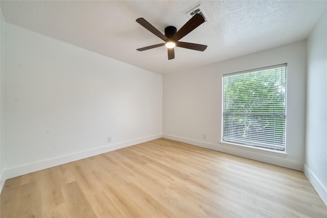 empty room featuring ceiling fan, a textured ceiling, visible vents, baseboards, and light wood-style floors