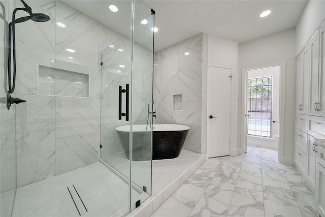 bathroom with recessed lighting, a freestanding tub, a marble finish shower, and marble finish floor