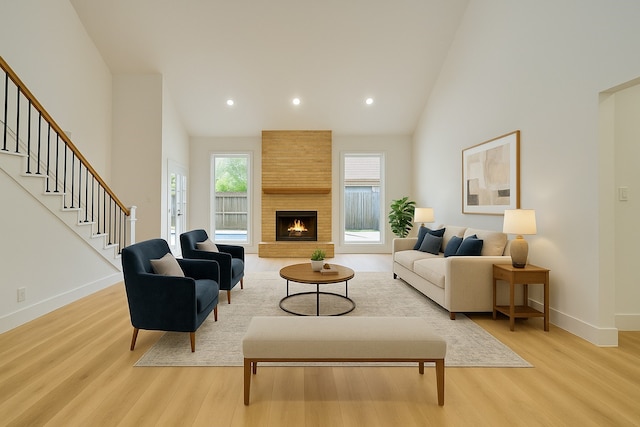 living area featuring light wood-style floors, high vaulted ceiling, recessed lighting, baseboards, and stairway