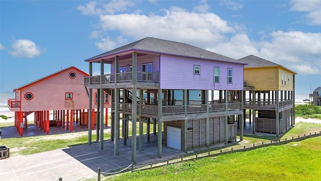 975 S Stingaree, Crystal Beach, TX 77650 - back of property featuring an attached garage, concrete driveway, a lawn, a deck, and a balcony