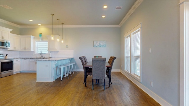 975 S Stingaree, Crystal Beach, TX 77650 - dining room with dark wood finished floors, ornamental molding, baseboards, and recessed lighting