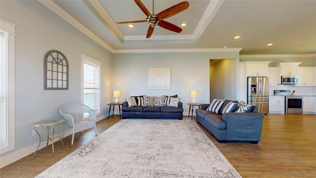 975 S Stingaree, Crystal Beach, TX 77650 - living area featuring a tray ceiling, ornamental molding, a ceiling fan, wood finished floors, and baseboards