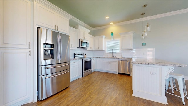 975 S Stingaree, Crystal Beach, TX 77650 - kitchen featuring appliances with stainless steel finishes, a peninsula, white cabinets, decorative backsplash, and light wood-type flooring
