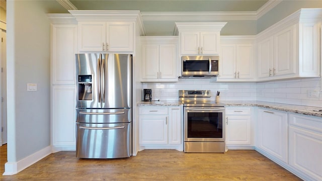 975 S Stingaree, Crystal Beach, TX 77650 - kitchen featuring appliances with stainless steel finishes, white cabinetry, light wood-type flooring, and ornamental molding