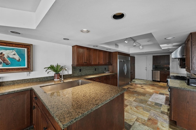 18 S Shore Dr S, Galveston, TX 77551 - kitchen featuring wall chimney exhaust hood, a tray ceiling, a sink, dark stone countertops, and stainless steel appliances