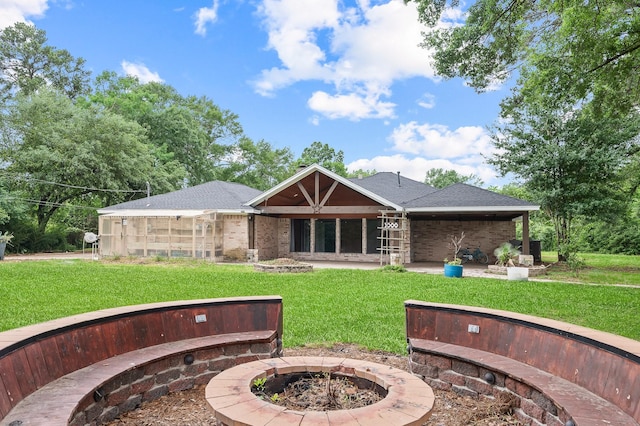 rear view of property with a yard, roof with shingles, and an outdoor fire pit