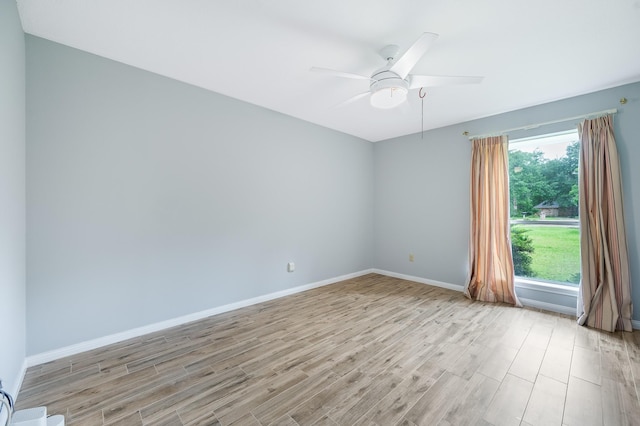 spare room with baseboards, ceiling fan, a healthy amount of sunlight, and light wood finished floors