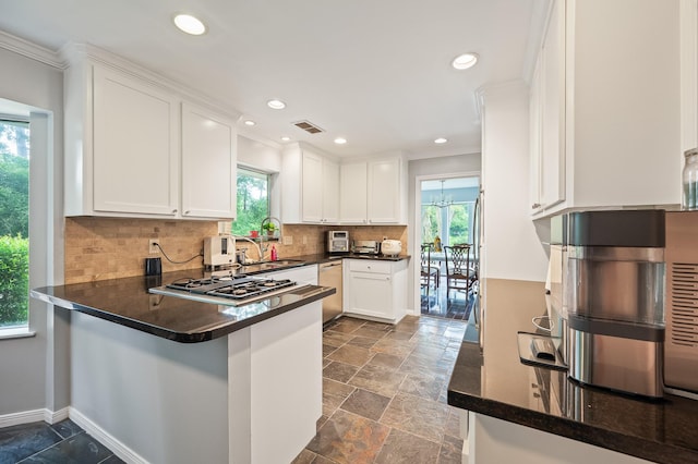 kitchen featuring stainless steel appliances, visible vents, ornamental molding, and stone tile flooring