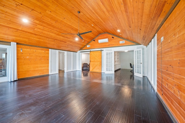 interior space with a barn door, wood ceiling, lofted ceiling, and wooden walls