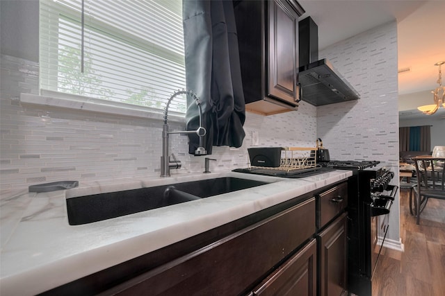 kitchen featuring decorative backsplash, wood finished floors, dark brown cabinets, light countertops, and black gas range