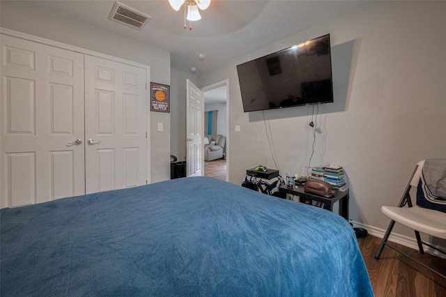 bedroom featuring visible vents, a closet, wood finished floors, baseboards, and ceiling fan