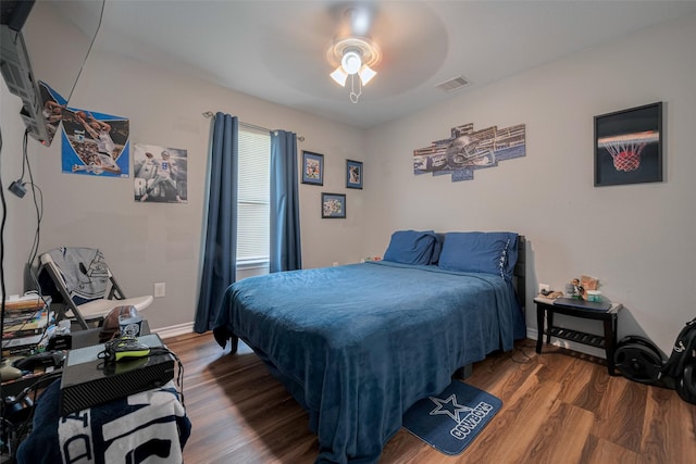 bedroom with baseboards, ceiling fan, wood finished floors, and visible vents
