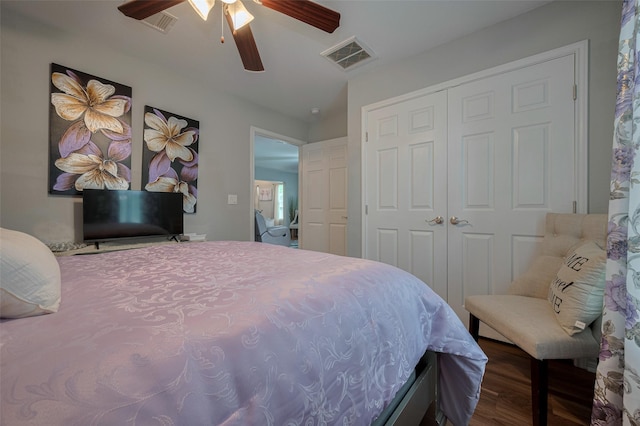 bedroom featuring a ceiling fan, visible vents, wood finished floors, and a closet