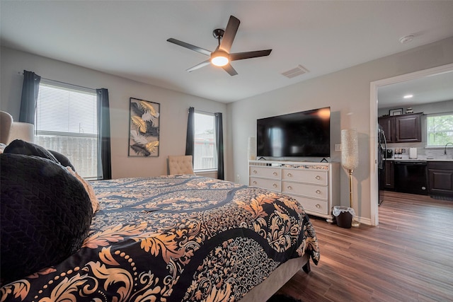 bedroom featuring ceiling fan, visible vents, black fridge, and wood finished floors