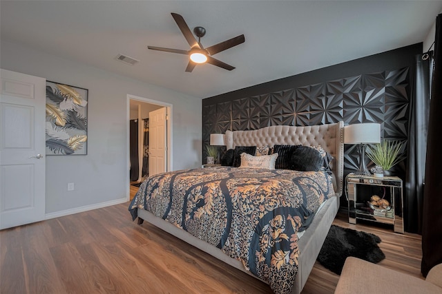 bedroom featuring ceiling fan, baseboards, visible vents, and wood finished floors