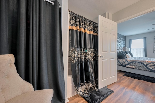 full bathroom featuring shower / bathtub combination with curtain, wood finished floors, and ensuite bathroom