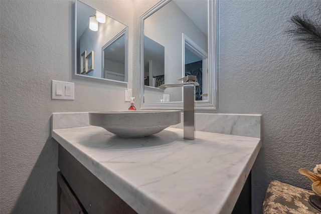 bathroom with a textured wall and vanity