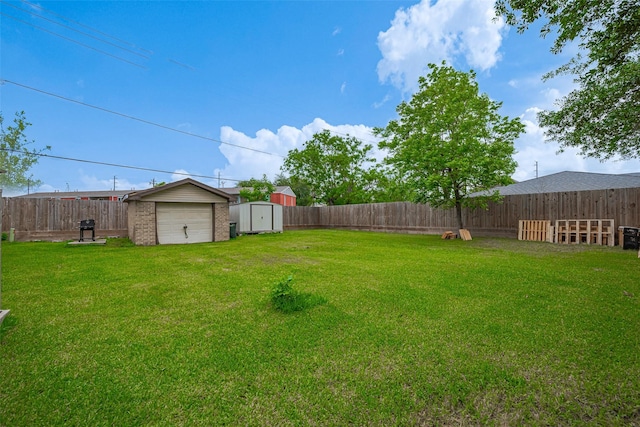 view of yard featuring a storage unit, a fenced backyard, an outbuilding, and a detached garage