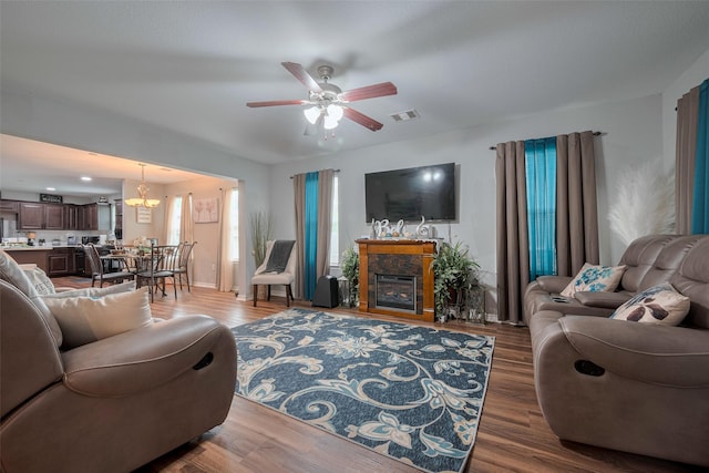 living room with visible vents, ceiling fan with notable chandelier, and wood finished floors