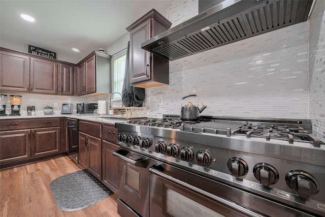 kitchen featuring light countertops, decorative backsplash, double oven range, and wall chimney exhaust hood