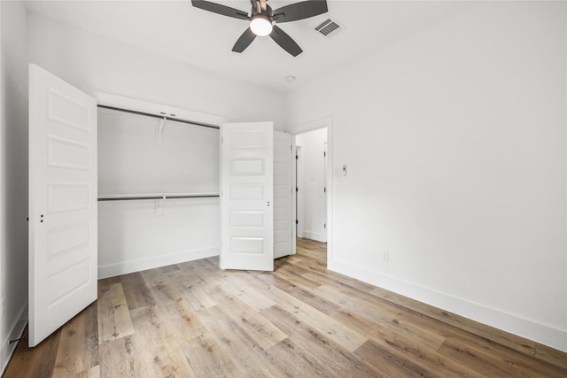 unfurnished bedroom featuring a ceiling fan, visible vents, wood finished floors, baseboards, and a closet