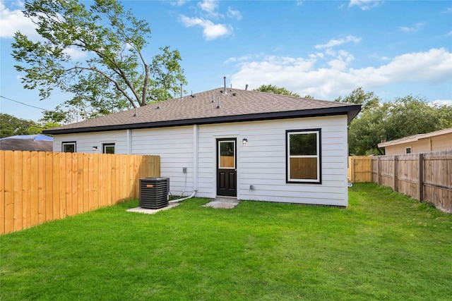 back of house with a fenced backyard, central AC unit, a yard, and roof with shingles
