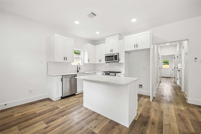 kitchen with visible vents, light wood-type flooring, white cabinets, a sink, and appliances with stainless steel finishes