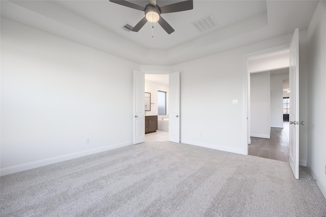 12810 Belford Gardens Dr, Humble, TX 77346 - unfurnished bedroom with carpet floors, baseboards, a tray ceiling, connected bathroom, and ceiling fan