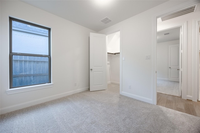 12810 Belford Gardens Dr, Humble, TX 77346 - unfurnished bedroom with light carpet, baseboards, and a walk in closet
