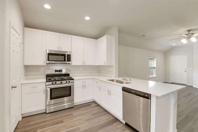 254 Cumberland Forest Dr, Magnolia, TX 77354 - kitchen with stainless steel appliances, a sink, light countertops, a peninsula, and light wood-type flooring