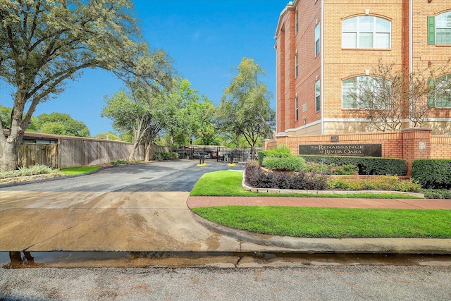 view of property's community with fence and concrete driveway