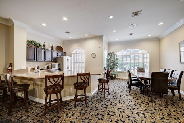kitchen with visible vents, freestanding refrigerator, a breakfast bar area, recessed lighting, and stainless steel microwave