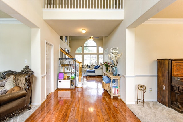 entryway with crown molding, stairs, ceiling fan, and wood finished floors