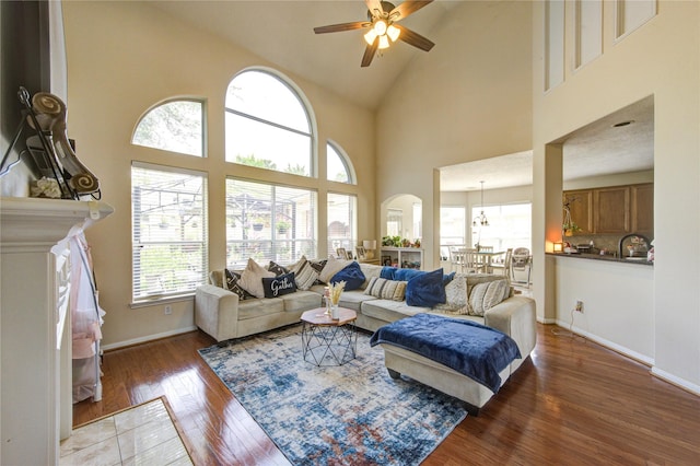 living room featuring a ceiling fan, high vaulted ceiling, baseboards, and hardwood / wood-style floors