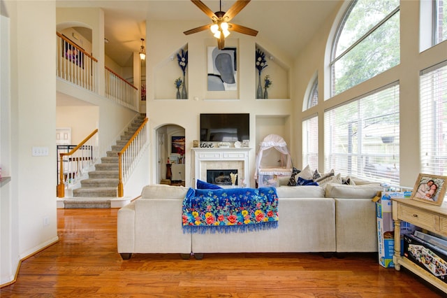 living room featuring a fireplace, wood finished floors, high vaulted ceiling, and ceiling fan