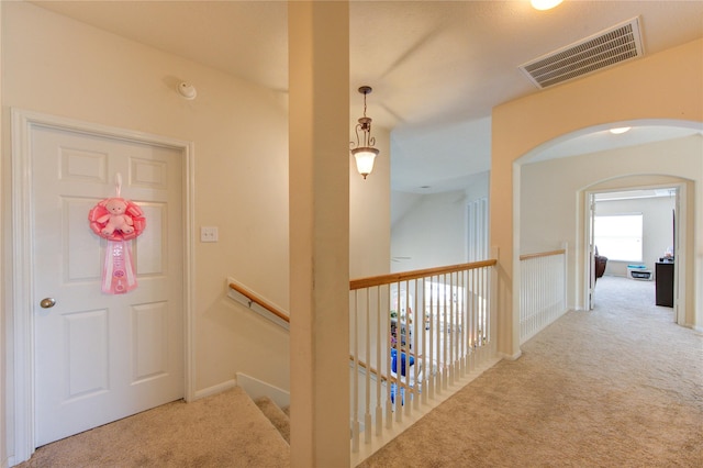 hall with carpet floors, arched walkways, and visible vents