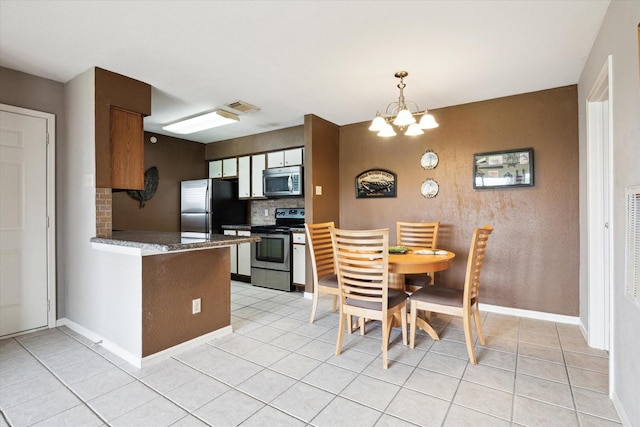 kitchen featuring dark countertops, stainless steel appliances, a peninsula, decorative backsplash, and visible vents