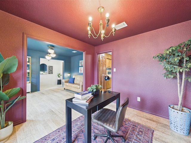 office area with carpet floors, a textured wall, and a chandelier