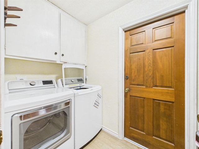 laundry room featuring baseboards, light wood finished floors, cabinet space, and washer and clothes dryer