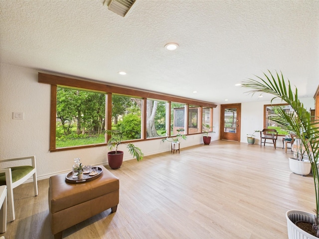 sitting room with a textured ceiling, baseboards, visible vents, and wood finished floors
