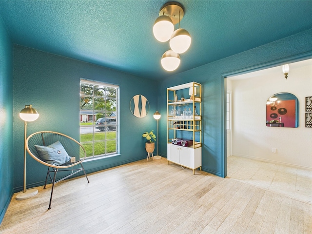 living area with a textured ceiling, baseboards, and wood finished floors