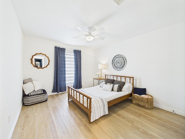 bedroom with baseboards, a ceiling fan, and light wood finished floors