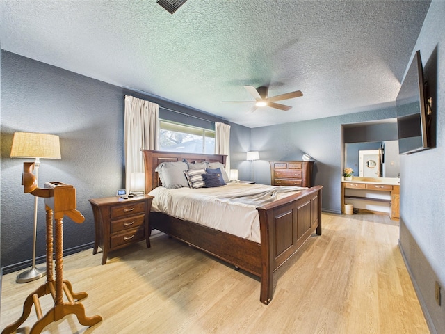 bedroom featuring a textured wall, light wood finished floors, a textured ceiling, a ceiling fan, and baseboards