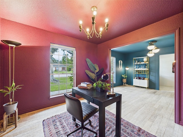 home office with a textured ceiling, a textured wall, and a notable chandelier
