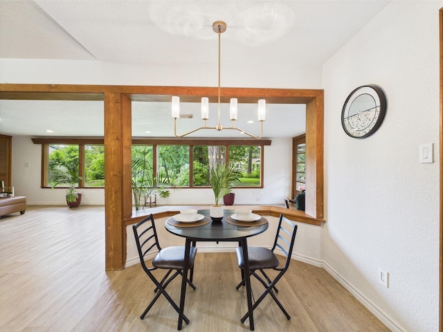 dining area featuring an inviting chandelier, light wood finished floors, and baseboards