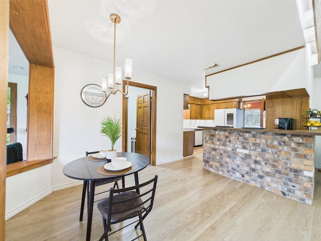 dining area with baseboards, an inviting chandelier, light wood-style flooring, and visible vents